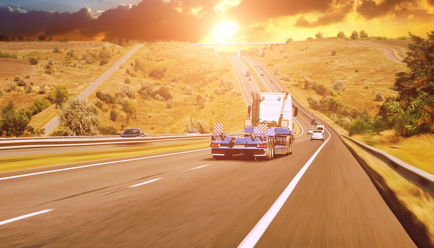 Sunrise over a hill with an Open flatbed on a highway