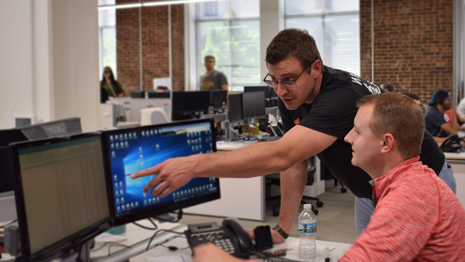 MySpot TMS employees pointing out shipping tracking data on a computer screen