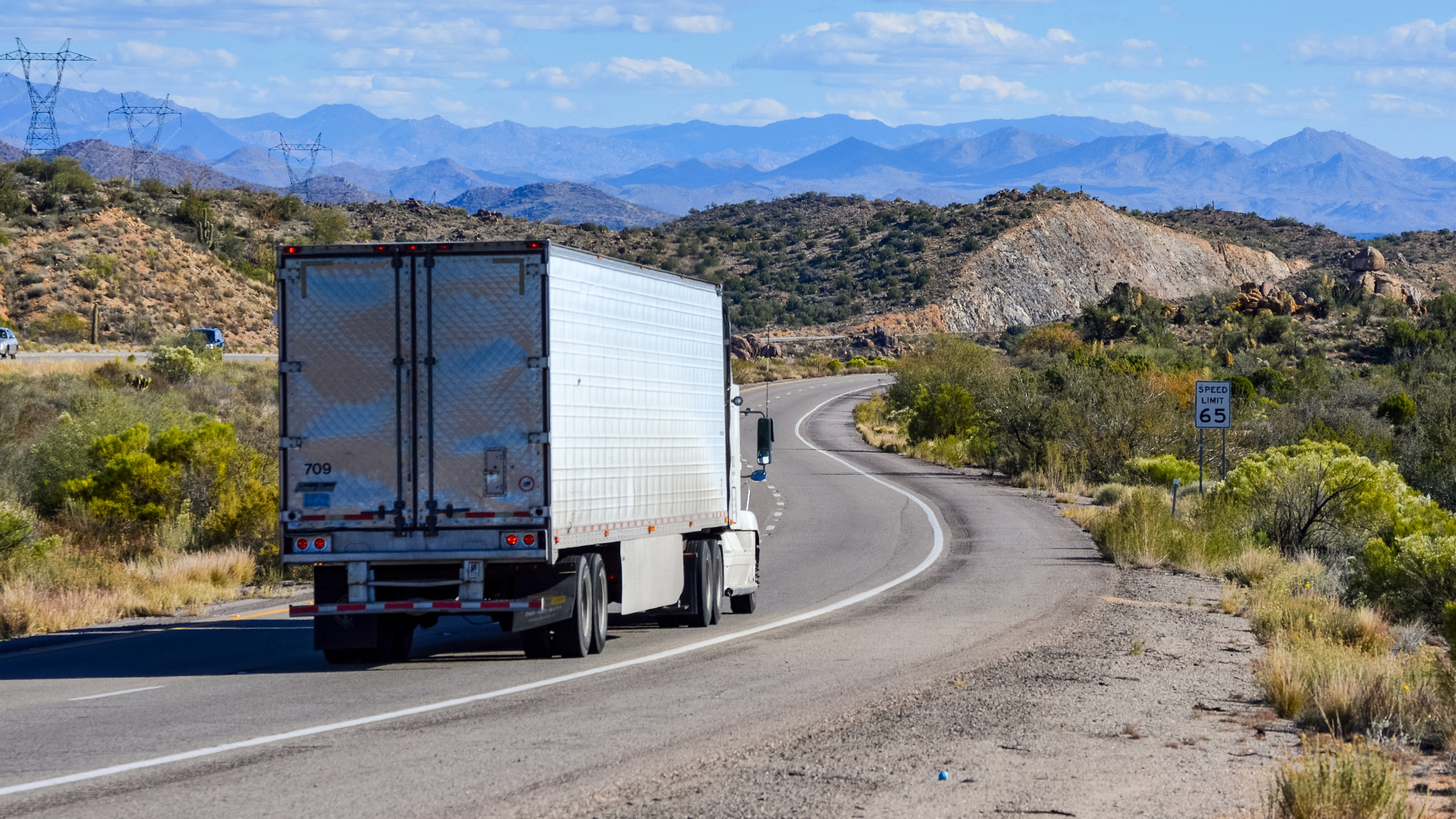 semi truck on a roadway with mountains and hills in the background