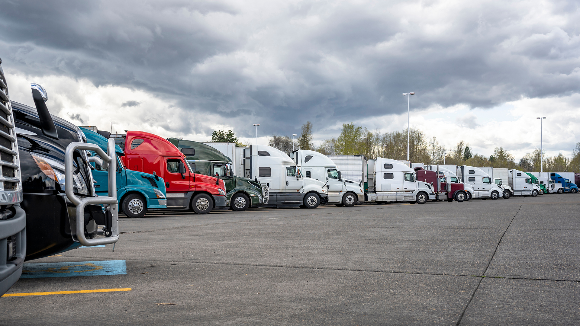 Fourteen semi trucks lined up in a parking lot