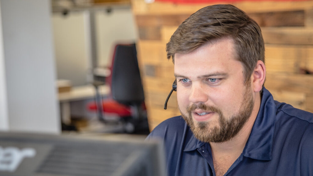 A MySpot TMS employee smiling on a headset talking to a shipper, carrier or driver