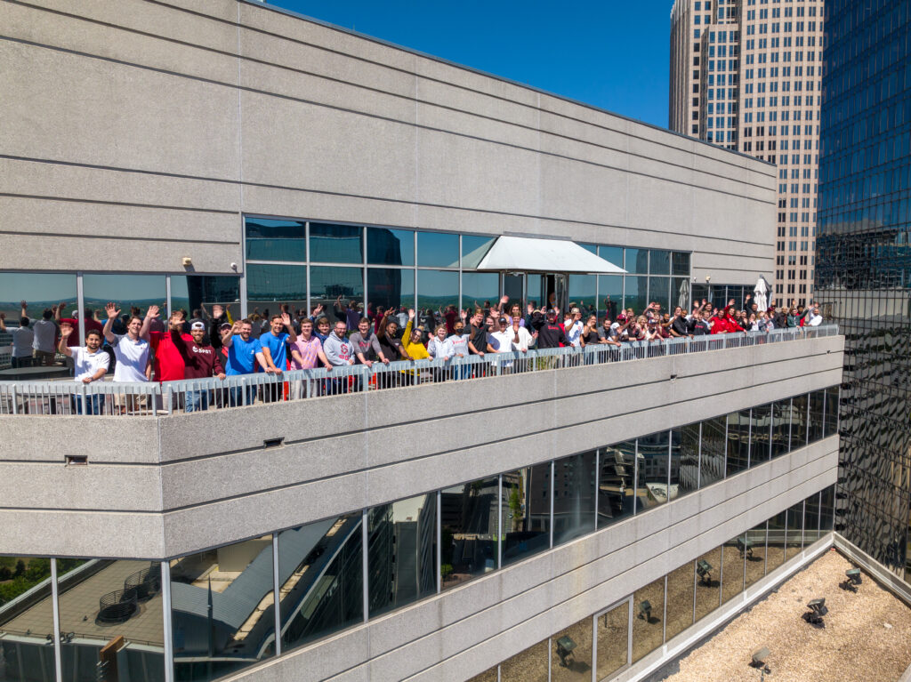 Drone photo showing employees waving and cheering on the balcony of Spot's Charlotte office.