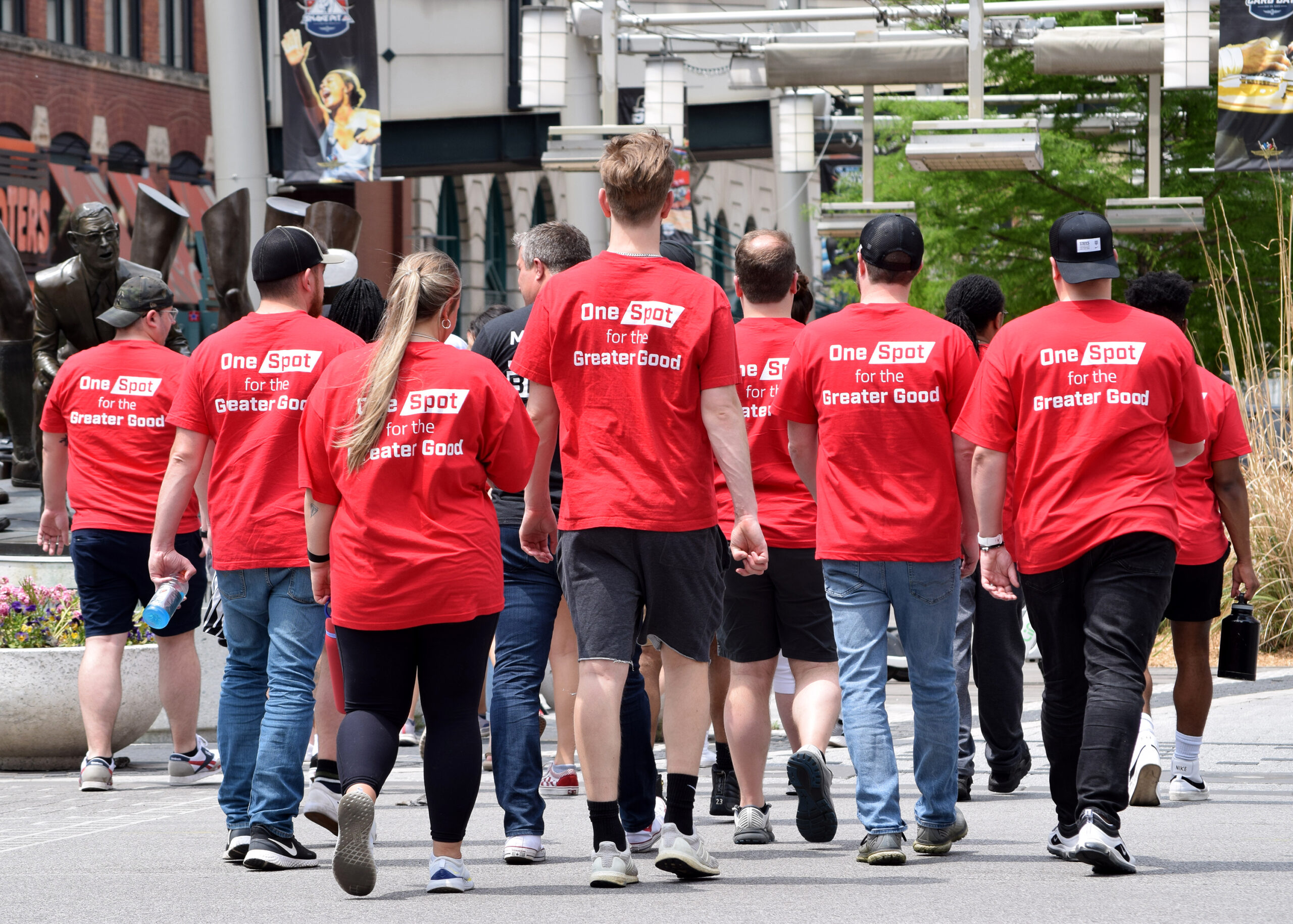 A group of Spot employees wearing read shirts walking down a street in Indianapolis. The shirts read 