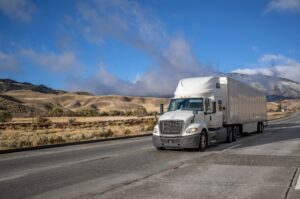A truck and trailer driving on an empty road to carry out truckload shipping