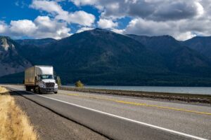 Semi truck hauling freight on a highway through a mountain landscape, representing long-haul trucking and national freight transportation logistics.
