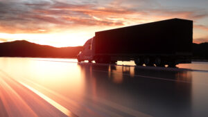 Semi truck on the road driving into the sunset.