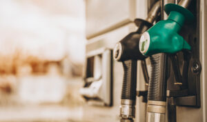 Close up photo of two gas pumps, one green and one black. The background is out of focus, and the pumps are in focus.