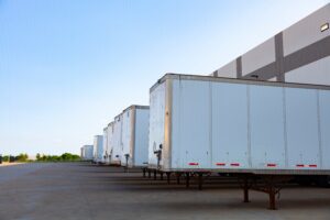 Row of white tractor trailers at a distribution center.