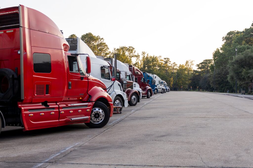 Row of semi trucks with red truck in the foreground